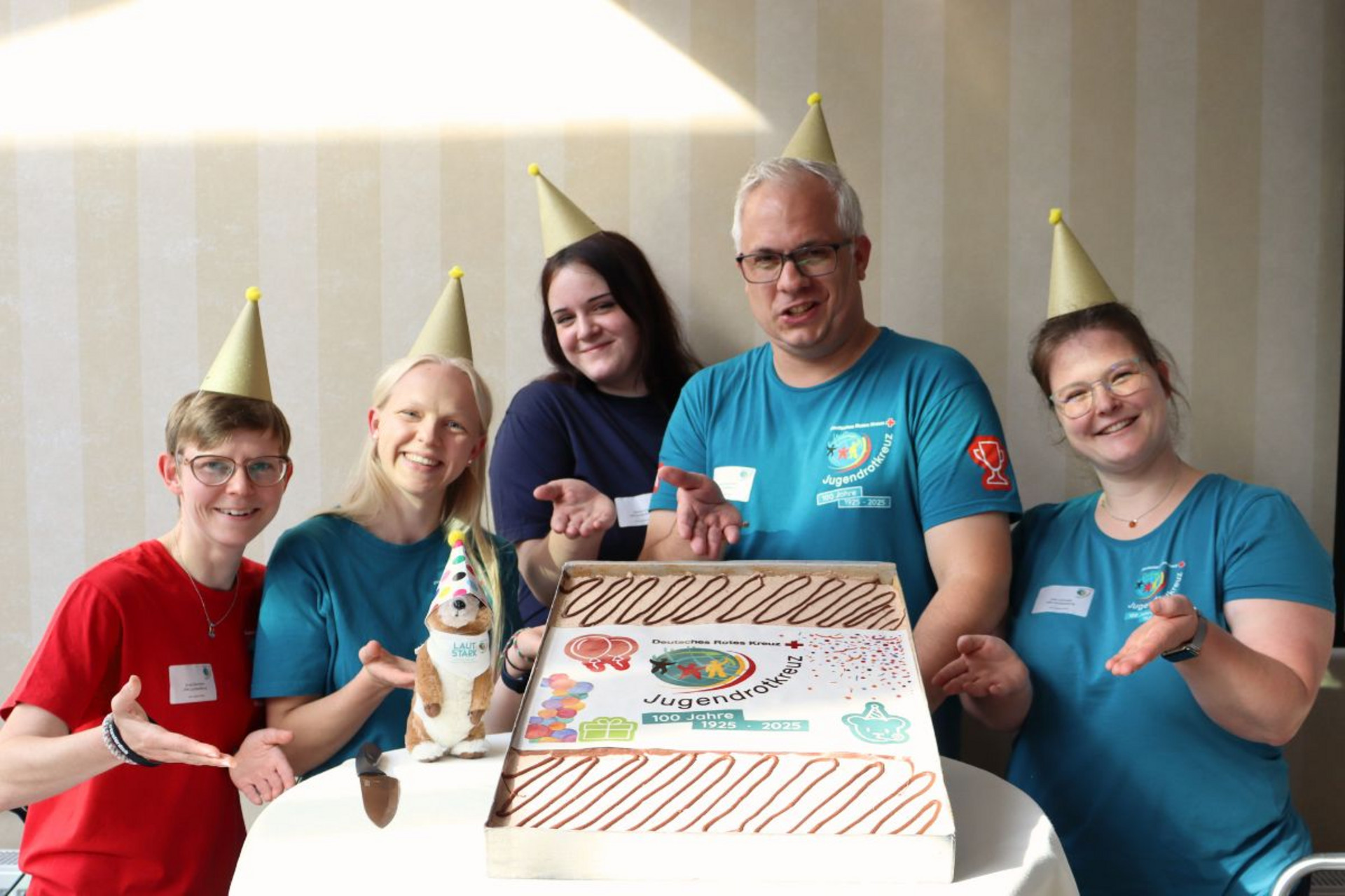 Die JRK-Landesleitung präsentiert eine Jubiläumstorte zum 100-Jährigen Bestehen des Jugendrotkreuz.