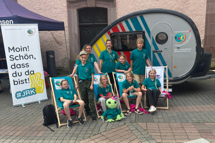 Eine JRK-Gruppe vor einem Wohnanhänger.