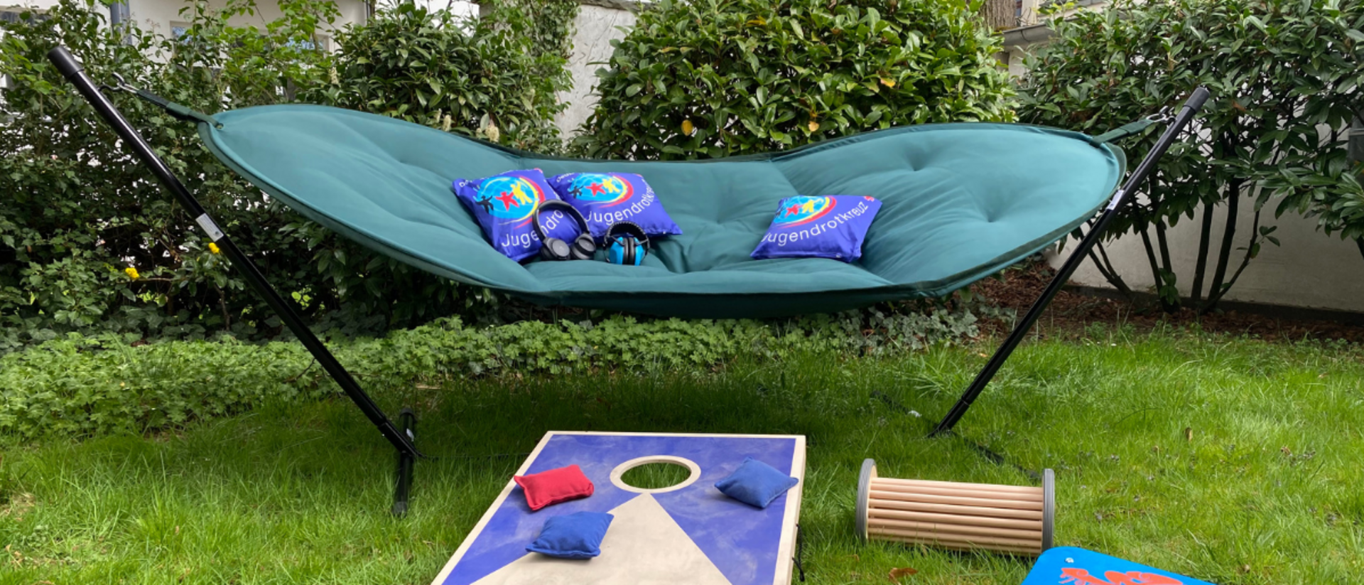 Pop-Up Store - Bleib in Balance Eine Hängematte auf Standfüßen, ein Balanceboard, ein Pedalo und ein Wurfspiel liegen auf einer Wiese.