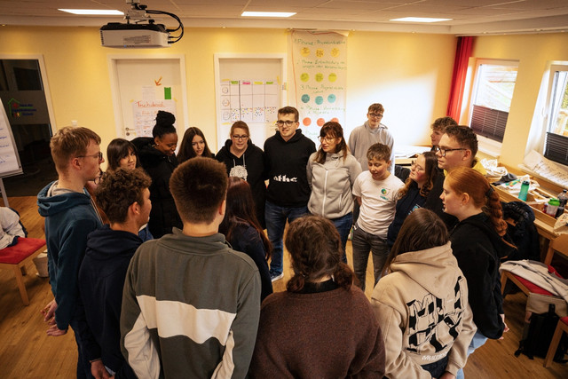 Teilnehmende eines Gruppenleitungskurses stehen im Kreis zusammen.