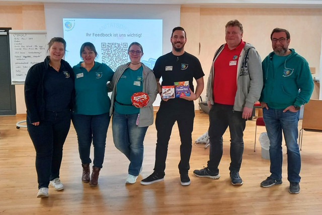 Sechs Mitglieder der Fachgruppe JRK und Schule stehen bei der Fachtagung Schulsanitätsdienst in einem Seminarraum.