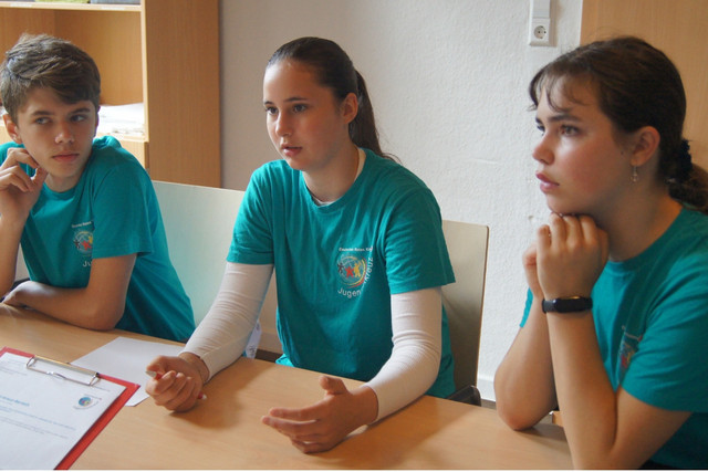 Drei SSD- Mitglieder in petrolfarbenen T-Shirts diskutieren.