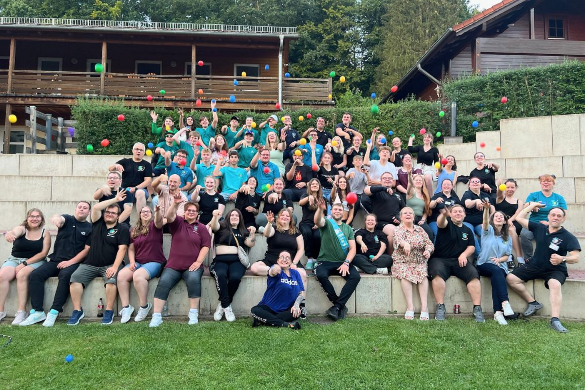 Auf einem Gruppenbild bei einem JRK-Event werfen die Teilnehmenden bunte Bälle Richtung Kamera.
